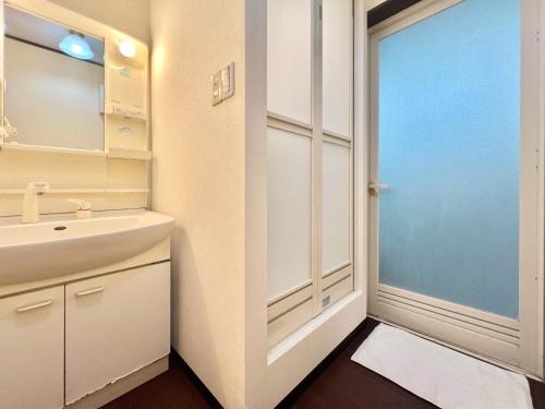 a bathroom with a sink and a mirror and a door at 西川口ハウス最大12名家族団体 in Toda