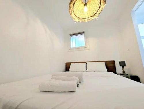 une chambre avec un grand lit blanc avec un lustre dans l'établissement PERLE D ANTHEOR - Bord de mer, à Anthéor