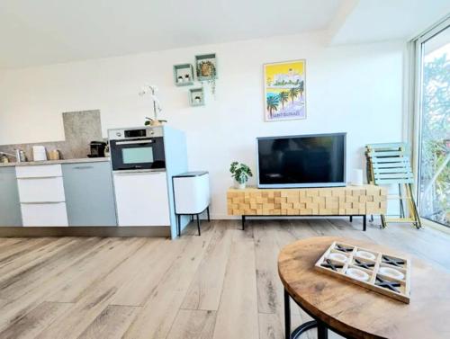 un salon avec une télévision et une table dans l'établissement PERLE D ANTHEOR - Bord de mer, à Anthéor