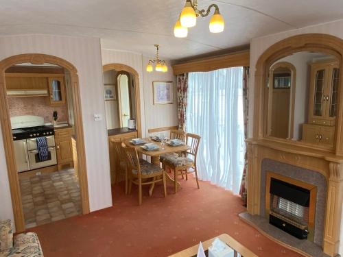 a kitchen and dining room with a table and a fireplace at Anchor's Drop in Blue Anchor