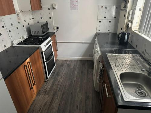 a small kitchen with a stove and a sink at Poshval in Manchester