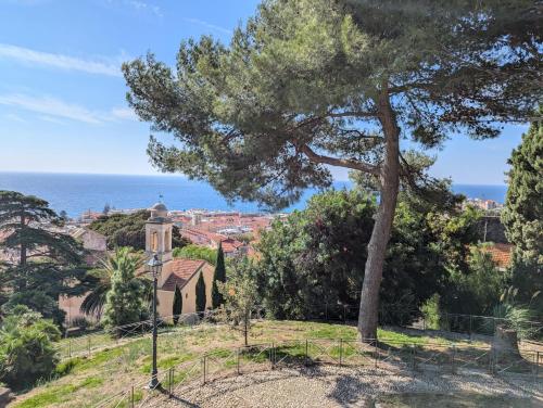 a tree on a hill with a church and the ocean at Casa Moret in Sanremo