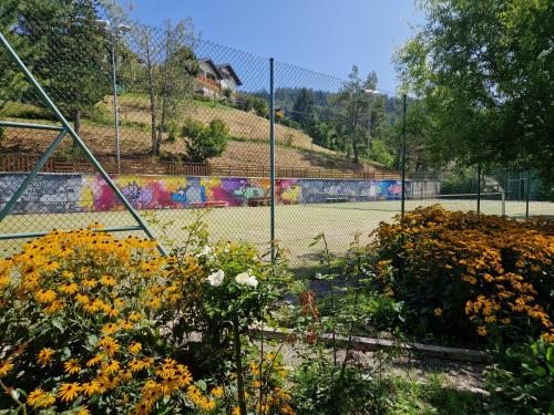 a tennis court with flowers in front of a fence at Chalet typique proche Crans Montana in Icogne