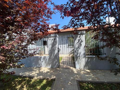 a white garage with a gate and some trees at El descanso in Ramallo
