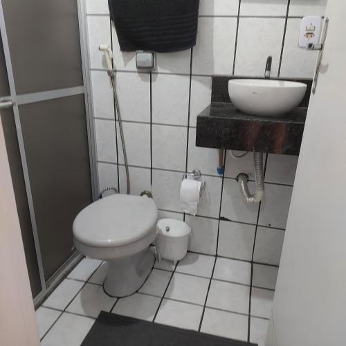 a small bathroom with a toilet and a sink at Apartamento Praia do Morro em Guarapari in Guarapari