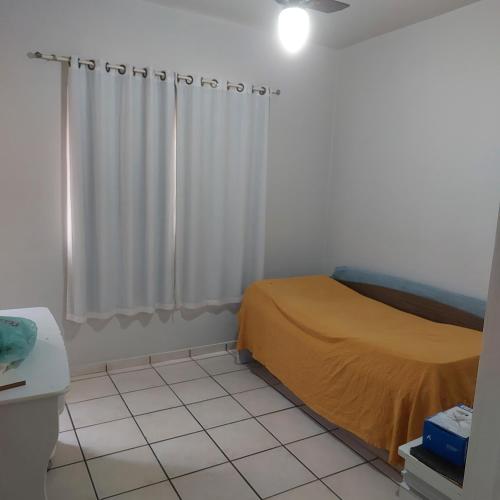 a small bedroom with a bed and a window at Apartamento Praia do Morro em Guarapari in Guarapari