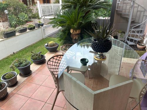 a glass table with chairs and potted plants on a patio at Flat with Jacuzzi - Casa Pia in Mondello