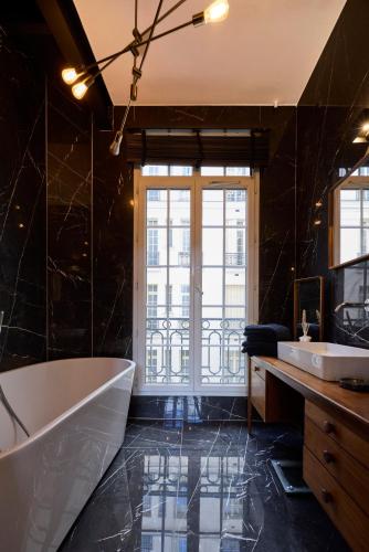 La salle de bains est pourvue d'une baignoire et de 2 lavabos. dans l'établissement Un Studio cosy au Cœur de Paris 17 Batignolles , Monceau, à Paris