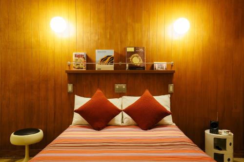 een slaapkamer met een bed met oranje kussens en houten wanden bij Spice Motel Okinawa in Kitanakagusuku