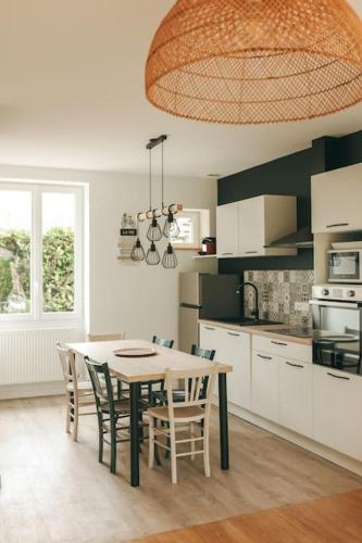 une cuisine avec une table et des chaises dans une cuisine dans l'établissement maison en ville Karine et Flavie, à Flacé-lès-Mâcon