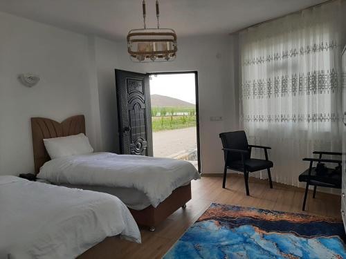 a bedroom with two beds and a chair and a window at Parasut Village Hotel in Kargakonmaz