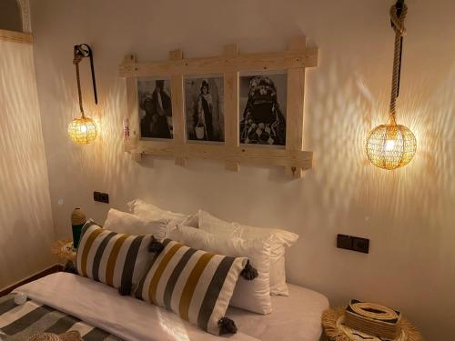 a bedroom with a bed with two lights and some pillows at Dar Mgouna Roses in Kalaat MGouna