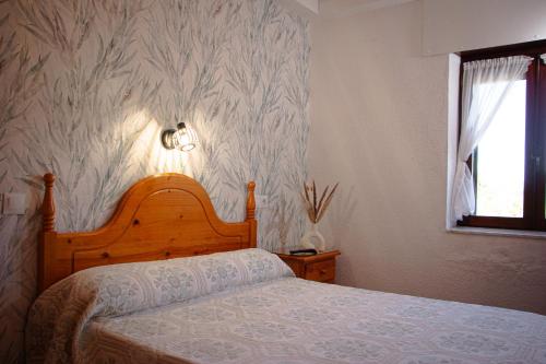 a bedroom with a bed with a wooden headboard and a window at COSMA HOUSE in Hinojedo
