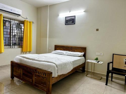 a bedroom with a large wooden bed with yellow curtains at Girivalam Vista Residency in Tiruvannāmalai