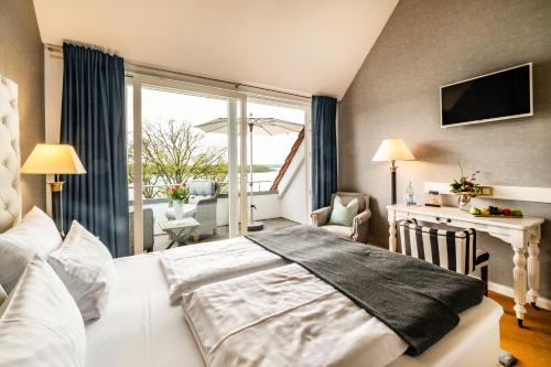 a bedroom with a white bed and a balcony at Seehotel Lichtenberg in Lichtenberg