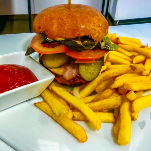 a hamburger and french fries on a plate with ketchup at Hotel Viwaldi in Baruchowo