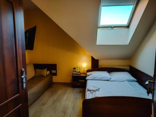 a bedroom with a bed and a window and a couch at Hotel Viwaldi in Baruchowo