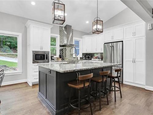 a kitchen with white cabinets and a black island with bar stools at Georgia Lakeside Getaway with Private Pool in Flowery Branch