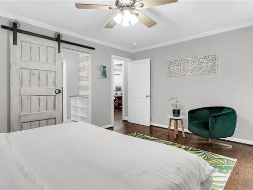 a bedroom with a bed and a ceiling fan and a green chair at Georgia Lakeside Getaway with Private Pool in Flowery Branch