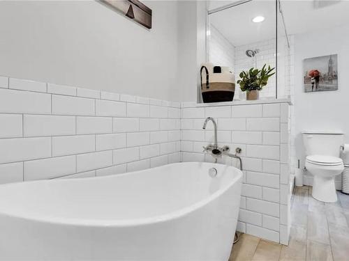a white bathroom with a tub and a toilet at Georgia Lakeside Getaway with Private Pool in Flowery Branch