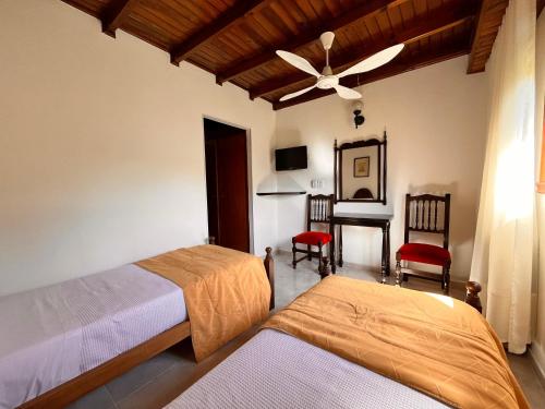 a bedroom with two beds and a desk with a ceiling fan at Hotel Olimpia in Ostende