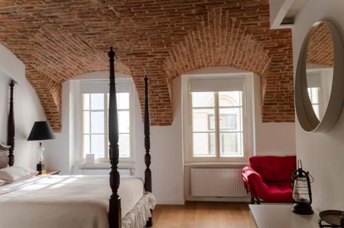 a bedroom with a bed and a red chair at Fantabulous Old Town Condo in Zagreb