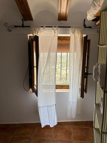 a window with white curtains in a bedroom at La Cueva in Vélez Blanco