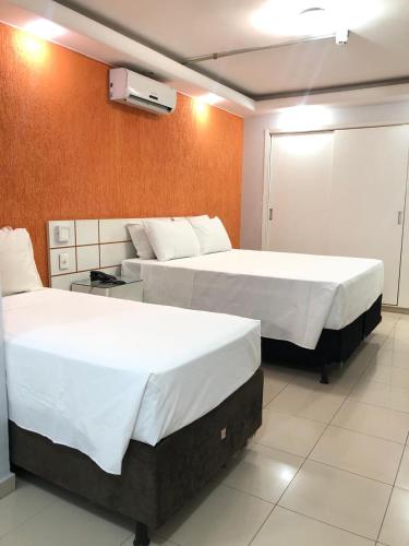 two beds in a hotel room with white sheets at Flat Centro de Brasília - Garvey Park Hotel 427 in Brasilia