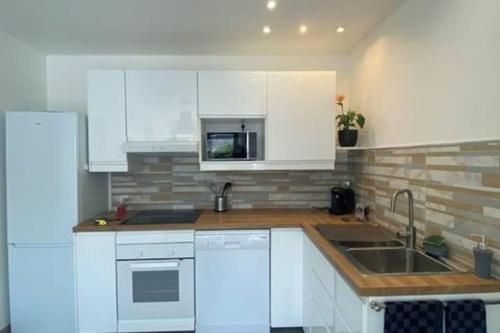 une cuisine avec des armoires blanches et un évier dans l'établissement Gîte à louer 70 m2, à La Chapelle-sur-Loire