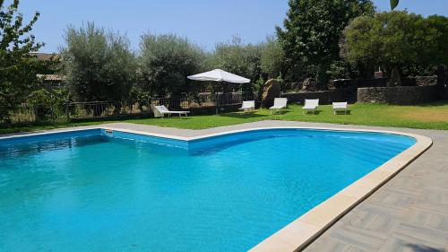 a swimming pool in a yard with chairs and an umbrella at Maison Divaga in Fleri