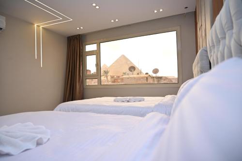 two beds in a room with a window at Pyramids Enigma Grand Lodge in Cairo
