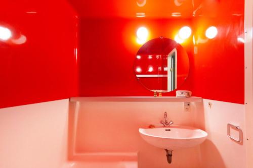 La salle de bains rouge est pourvue d'un lavabo et d'un miroir. dans l'établissement Résidence Lauzieres - Studio 5 personnes pied des pistes MAE-5044, à Arc 1800