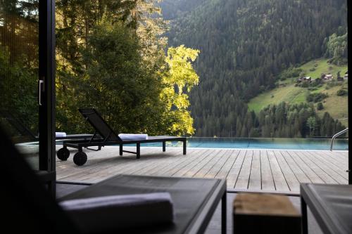 a chair on a deck with a view of a lake at Paznauner Villen - Villa II in Kappl