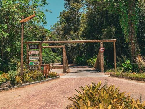 un arco di legno sopra un sentiero di mattoni in un giardino di Ilha do Sol a Arraial d'Ajuda