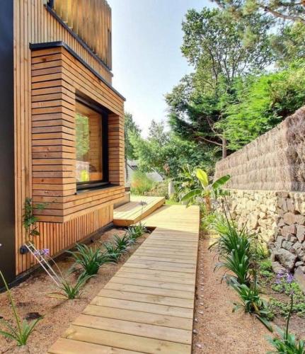 a wooden pathway leading to a house with a window at Villa Namasté SPA Hammam port & Mer in La Trinité-sur-Mer