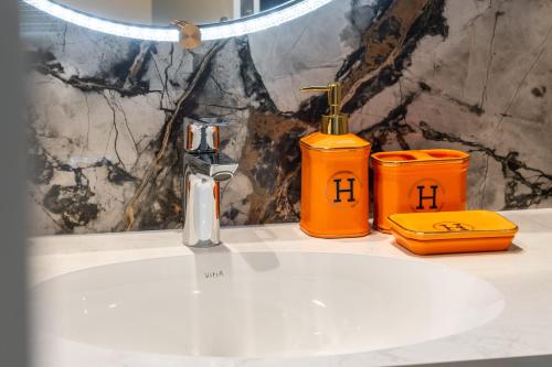 a bathroom sink with a faucet and two orange containers at Modern Apartment in Dubai Creek Harbour By DuStay in Dubai