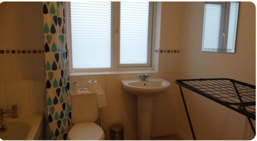 a bathroom with a toilet and a sink and a window at Family Friendly Room in Manchester