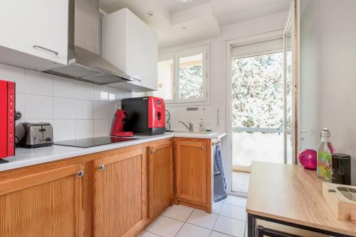 a kitchen with wooden cabinets and a red appliance at Les jardins de Rangueil, Parking, Métro, Piscine in Toulouse