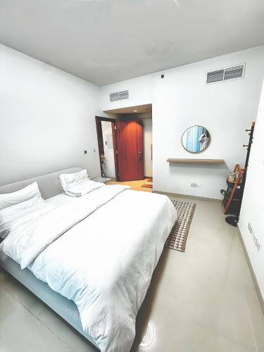 a white bedroom with a large bed and a mirror at Al Reem Breeze in Abu Dhabi