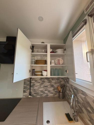 une cuisine avec des armoires blanches et un évier dans l'établissement Appartement 1 chambre à Thionville proche Luxembourg, à Thionville