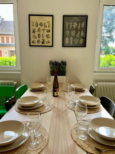 - une table avec des verres, des assiettes et une bouteille de vin dans l'établissement Chez Jean ! Au pied du vignoble, à 5 min de Colmar, à Ingersheim