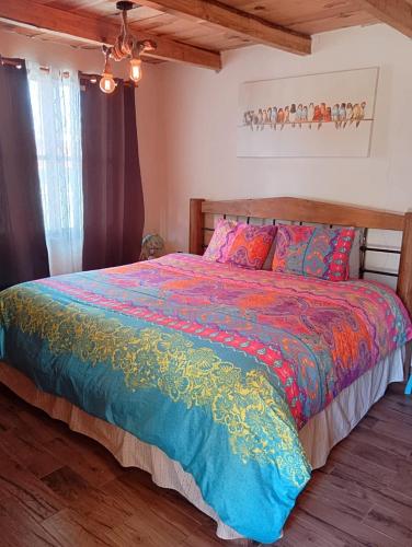 a bedroom with a bed with a colorful comforter at Acogedora cabaña cerca del desierto de los leones y CC santa Fe in Mexico City