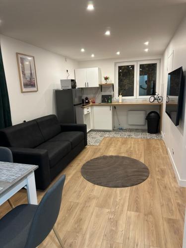 un salon avec un canapé noir et une cuisine dans l'établissement duplex apartment, à Montreuil