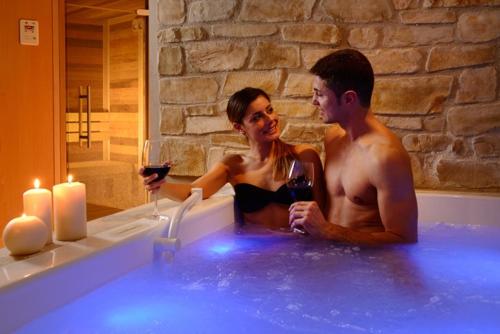 Un uomo e una donna seduti in una vasca da bagno con un bicchiere di vino di Hotel Mia Cara & Spa a Firenze