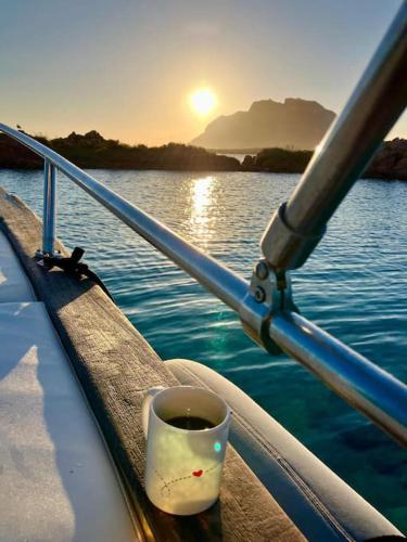 a cup of coffee sitting on the side of a boat at Sleeping on a boat in the Island's bay in Porto San Paolo