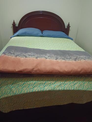 a bed with a wooden headboard and blue pillows on it at Albergue Camry Backpackers佳美背包客旅馆 in Cuenca