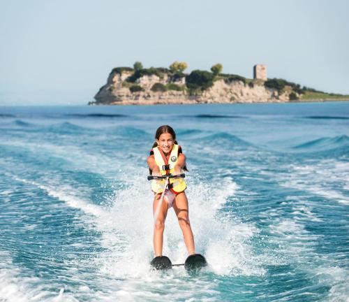 a girl is on water skis in the water at Sani Dunes in Sani Beach