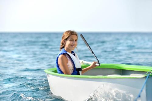 a girl is sitting in a boat in the water at Sani Dunes in Sani Beach