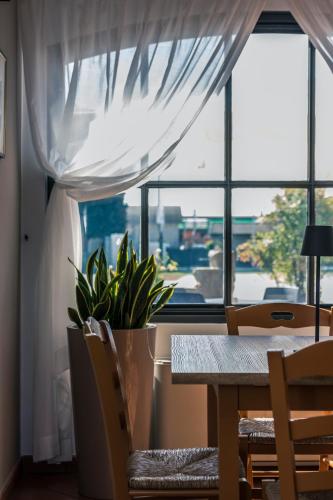 a dining room table with a potted plant in front of a window at Hotel Residence - Il Giardino del Cigno in Latisana