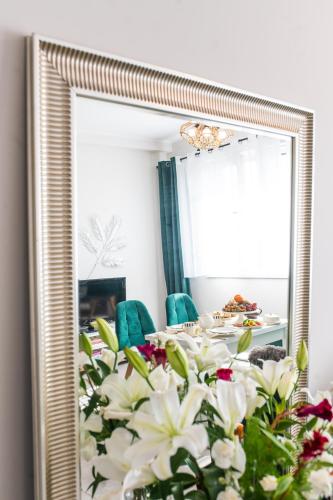 a table with white flowers in front of a mirror at Apartament Gościnny Czempion in Gniezno